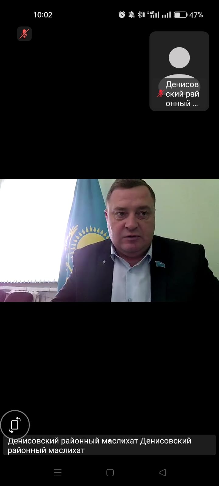 Қазақстан туының алдында тұрған костюм киген ер адамның бейнеқоңырау кезіндегі скриншоты.