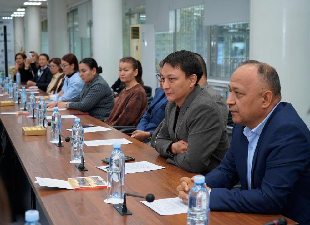 Жиналыс үстелінде отырған ресми киінген адамдар тобы.