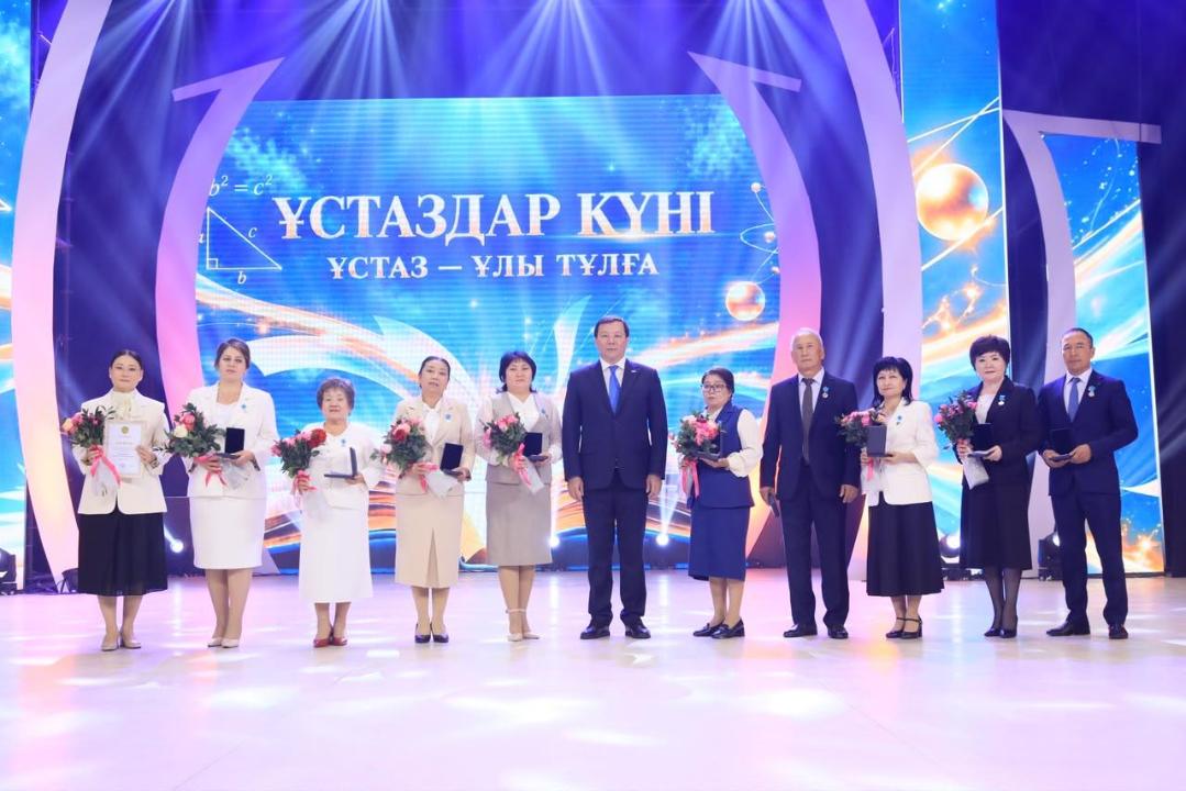 «Ұстаздар күні» мерекелік кешінде сахнада тұрған сыйлы мұғалімдер мен қонақтар.