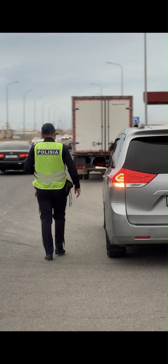 Жолда көліктердің арасында тұрған полиция қызметкері.