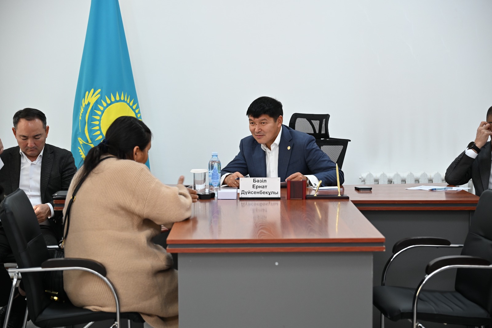 Келіссөз үстеліндегі адамдар және Қазақстан Республикасының туы.