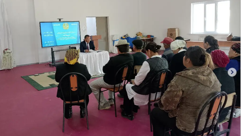 Экран алдында отырған адамдарға баяндама жасап жатқан әкім.