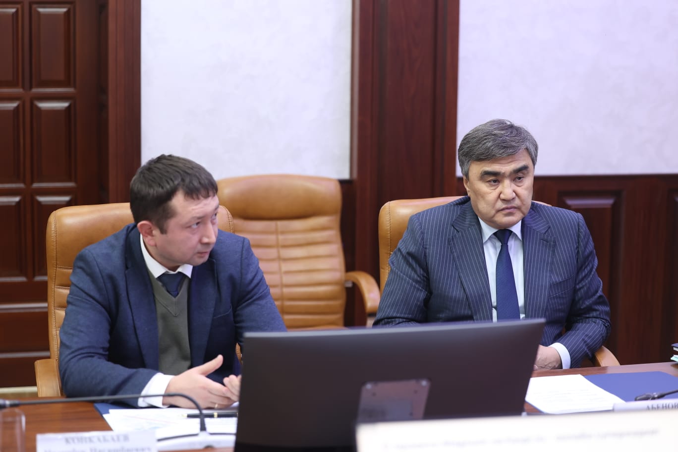 Жиналыста отырған екі ер адам.