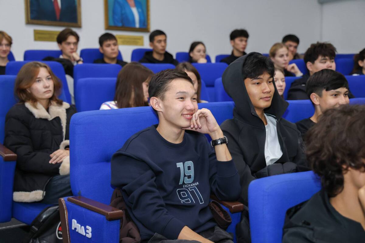 Көк орындықтарда дәріс тыңдап отырған студенттер тобы.