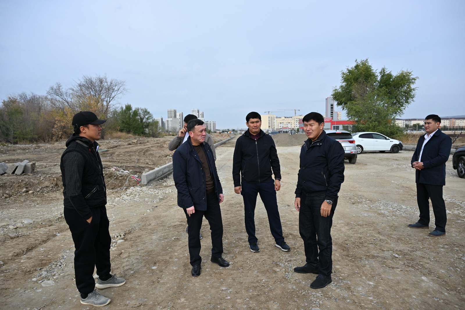 Құрылыс алаңында жиналған ерлер тобы.