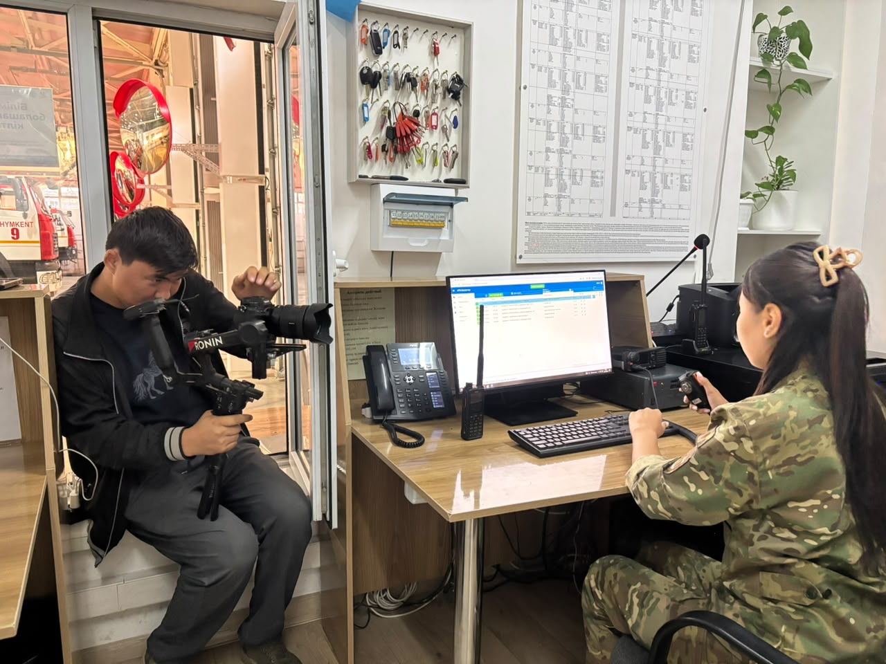 Оператор снимает на камеру женщину в военной форме, сидящую за компьютером в офисе.