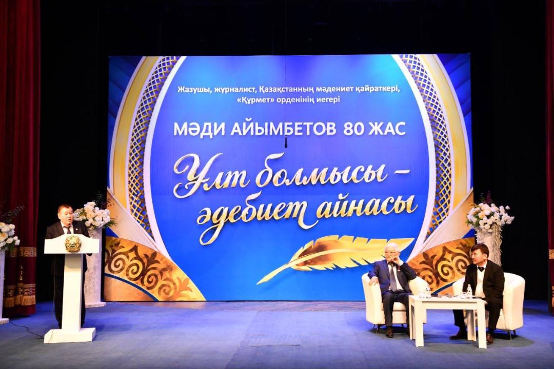 Мәди Айымбетовтің 80 жасқа толуына арналған мерекелік кеш. Сахнада спикерлер мен қонақтар.