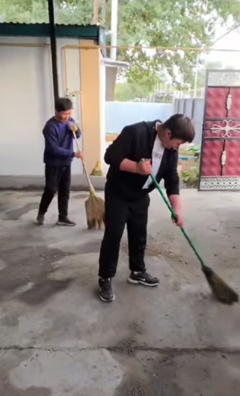Ауланы сыпырып жатқан екі жігіт.