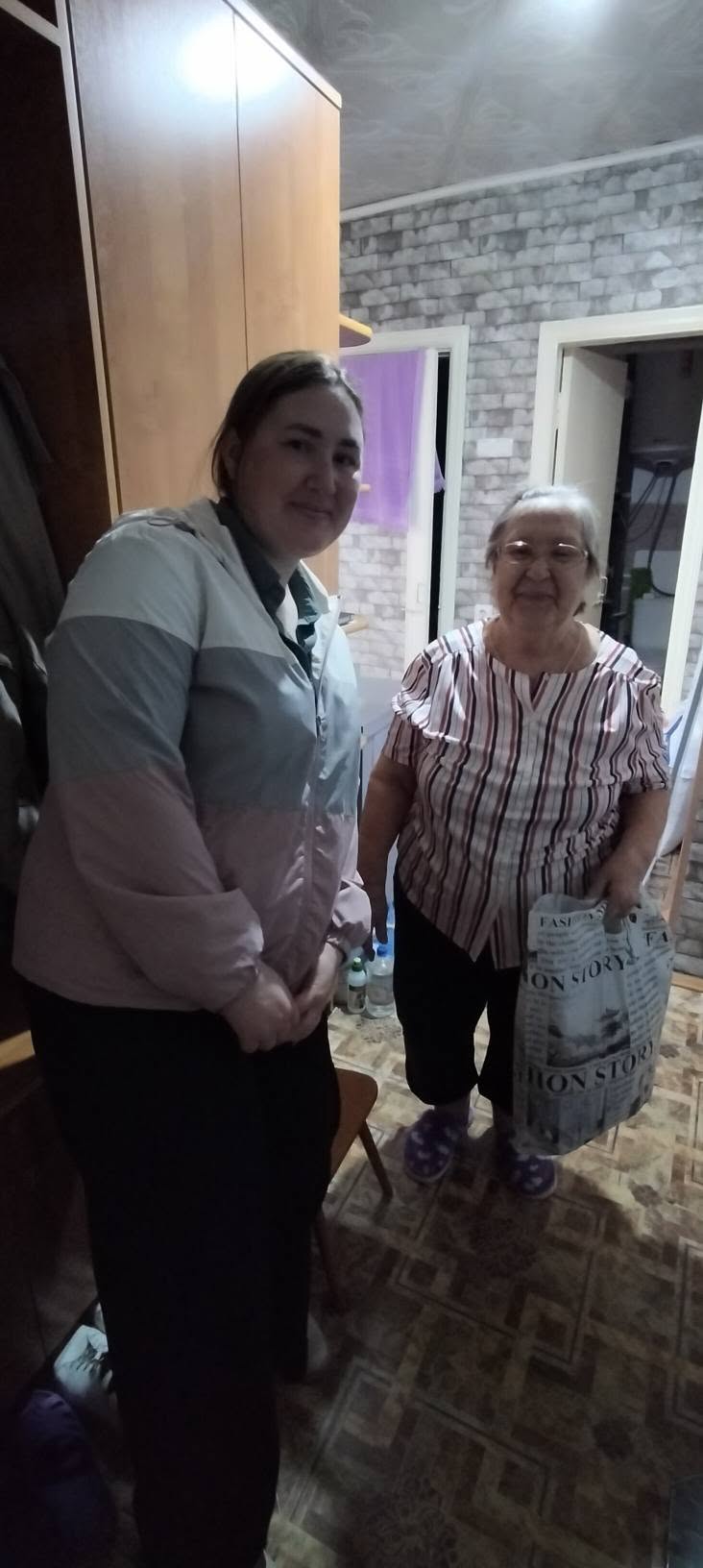 Бөлмеде тұрған екі әйелдің суреті.
