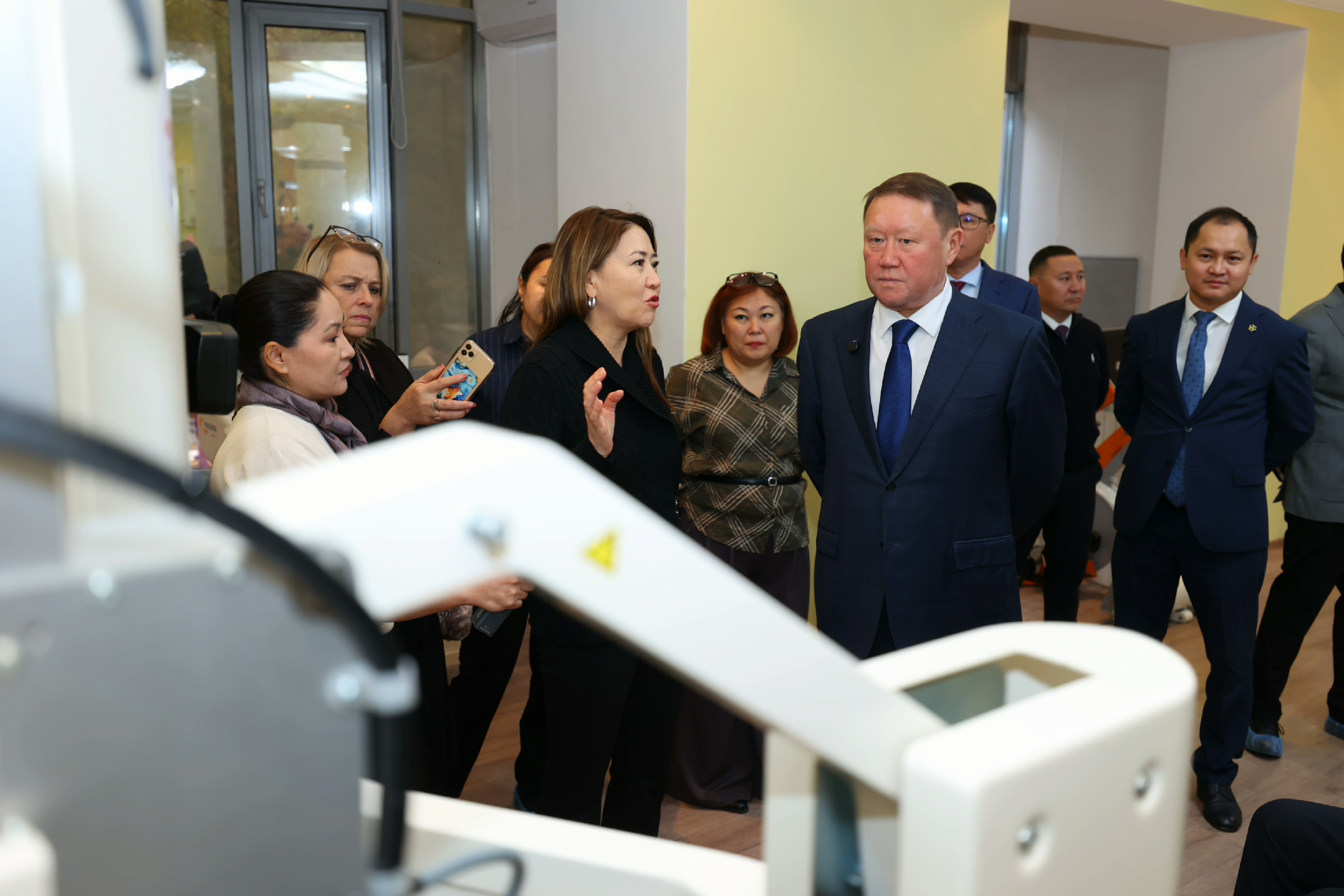Ресми киімдегі топтың медициналық жабдықты қарап тұрғаны.