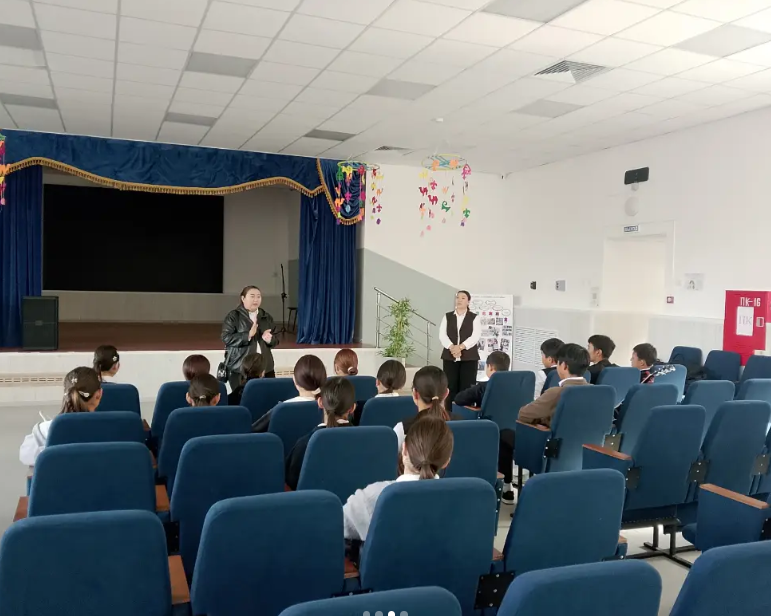 Актолдың сахнасында сөйлеп тұрған спикер және оны тыңдап отырған студенттер.