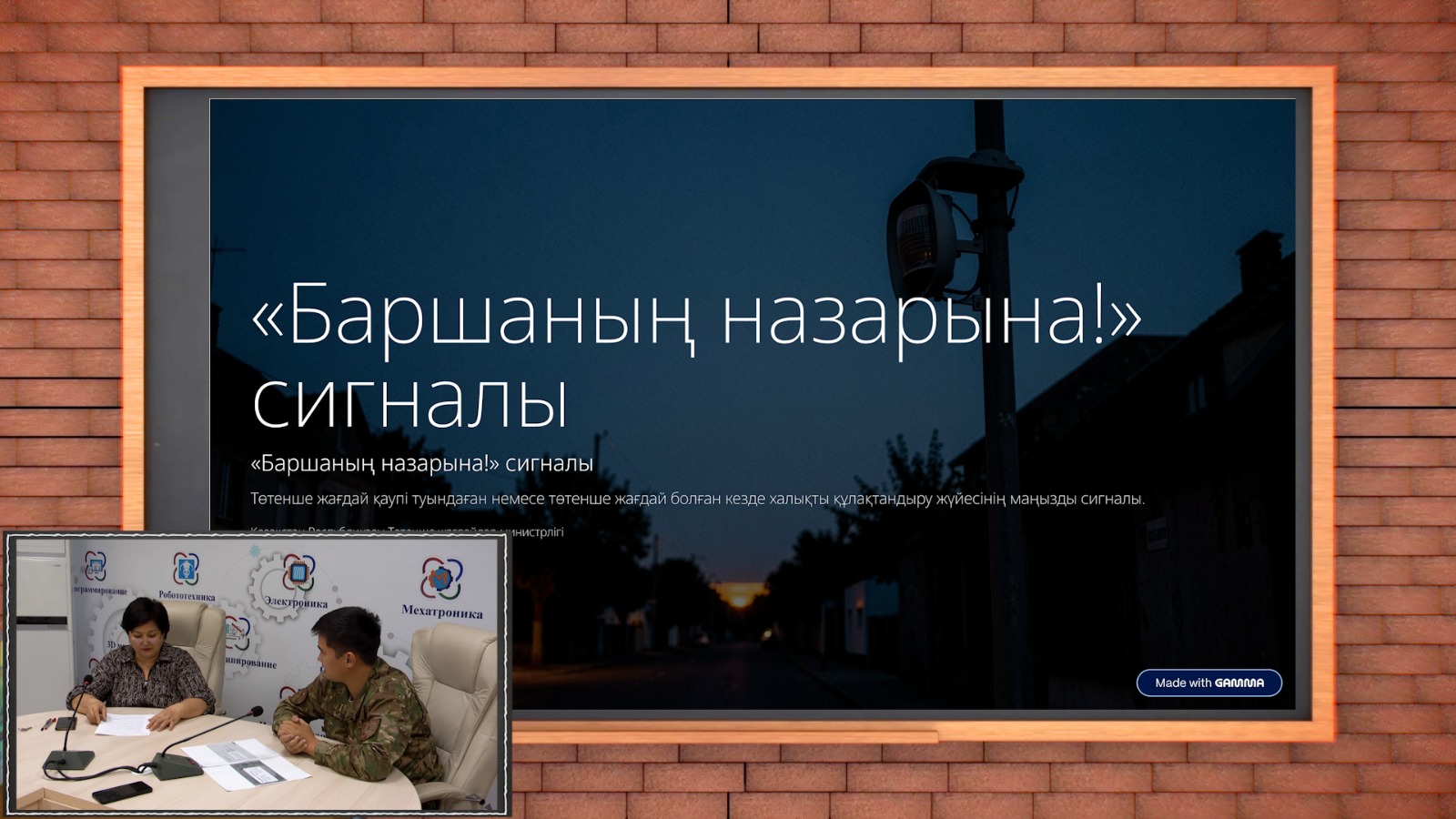 Экранда «Баршаның назарына!» сигналы туралы презентация көрсетіліп тұр, ал алдында екі адам отыр.