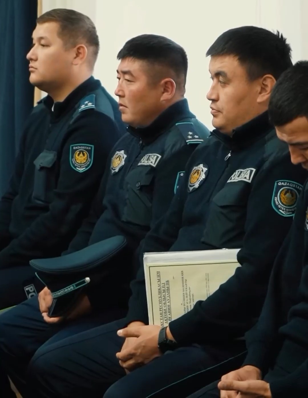Қазақстан полициясының формасындағы бірнеше қызметкердің отырып тұрған сәті.