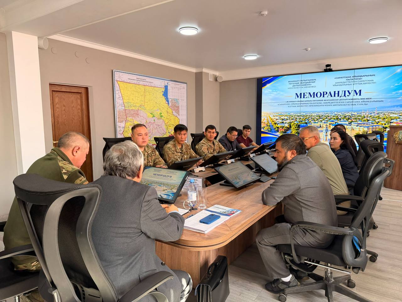 Келіссөз жүргізіп жатқан ресми тұлғалар мен әскери қызметкерлердің жиналысы. Фонда «Меморандум» жазылған экран тұр.