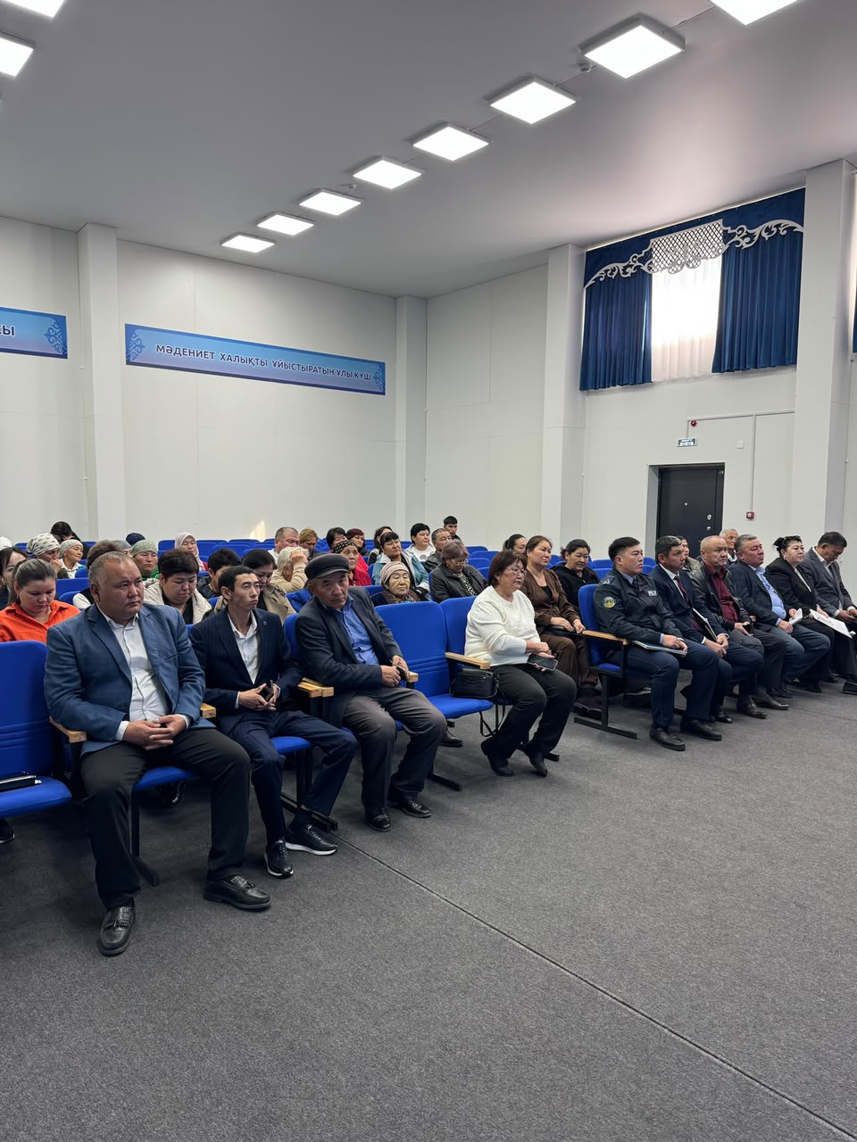 Жиналыс залында отырған адамдар тобы.