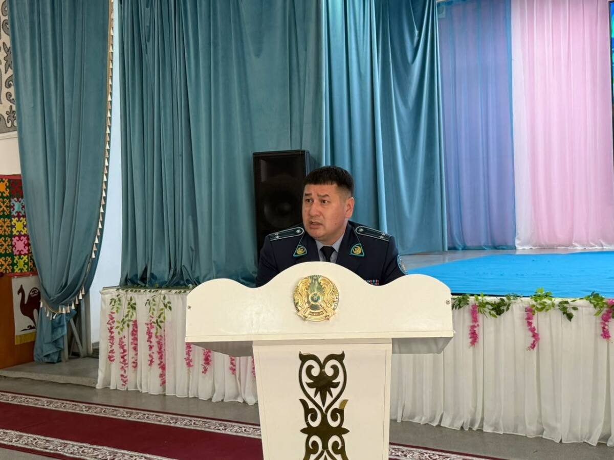 Форма киген ер адам трибунада сөйлеп тұр.