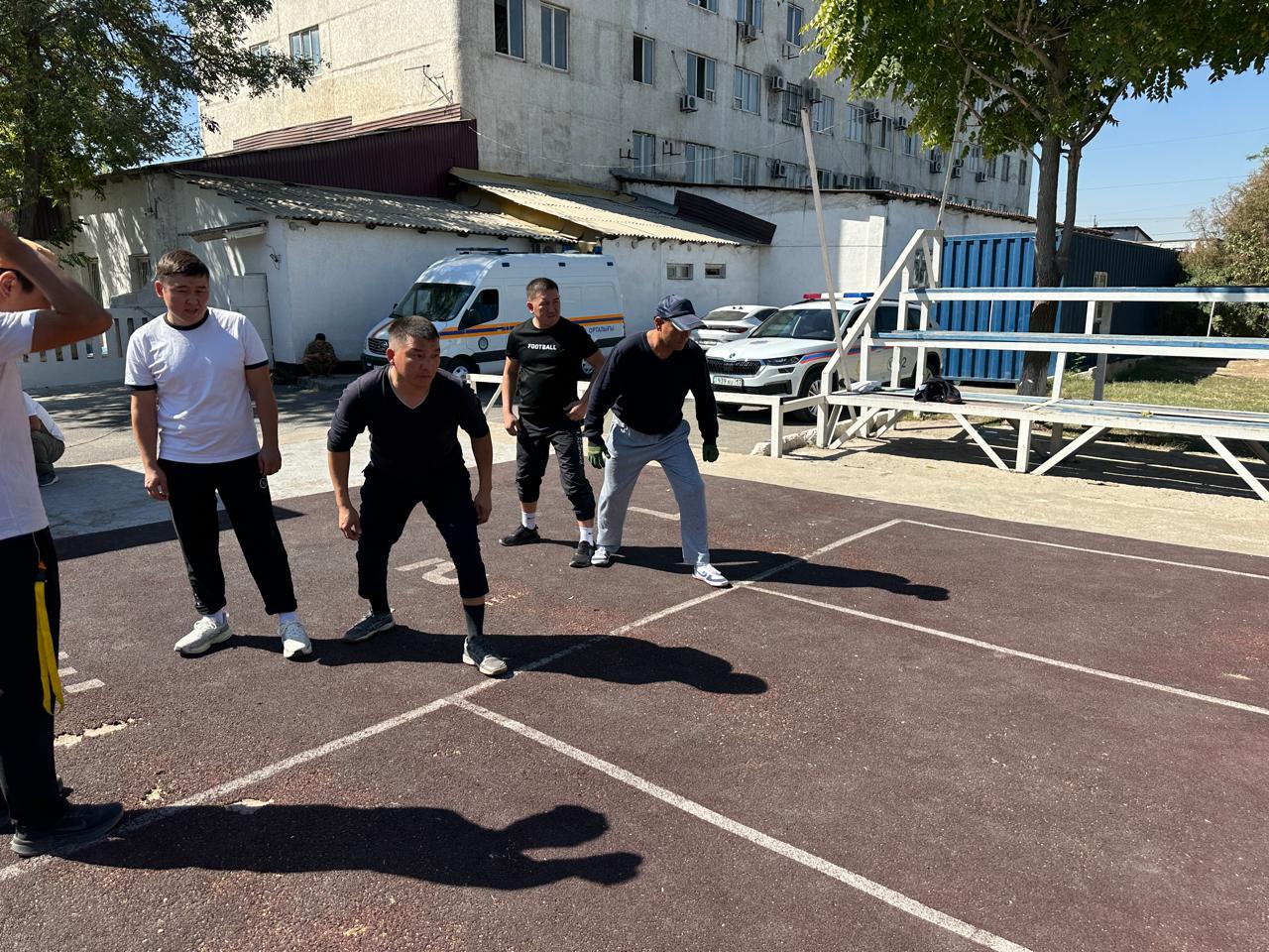 Спорт алаңында жаттығу жасап жатқан жас жігіттер.