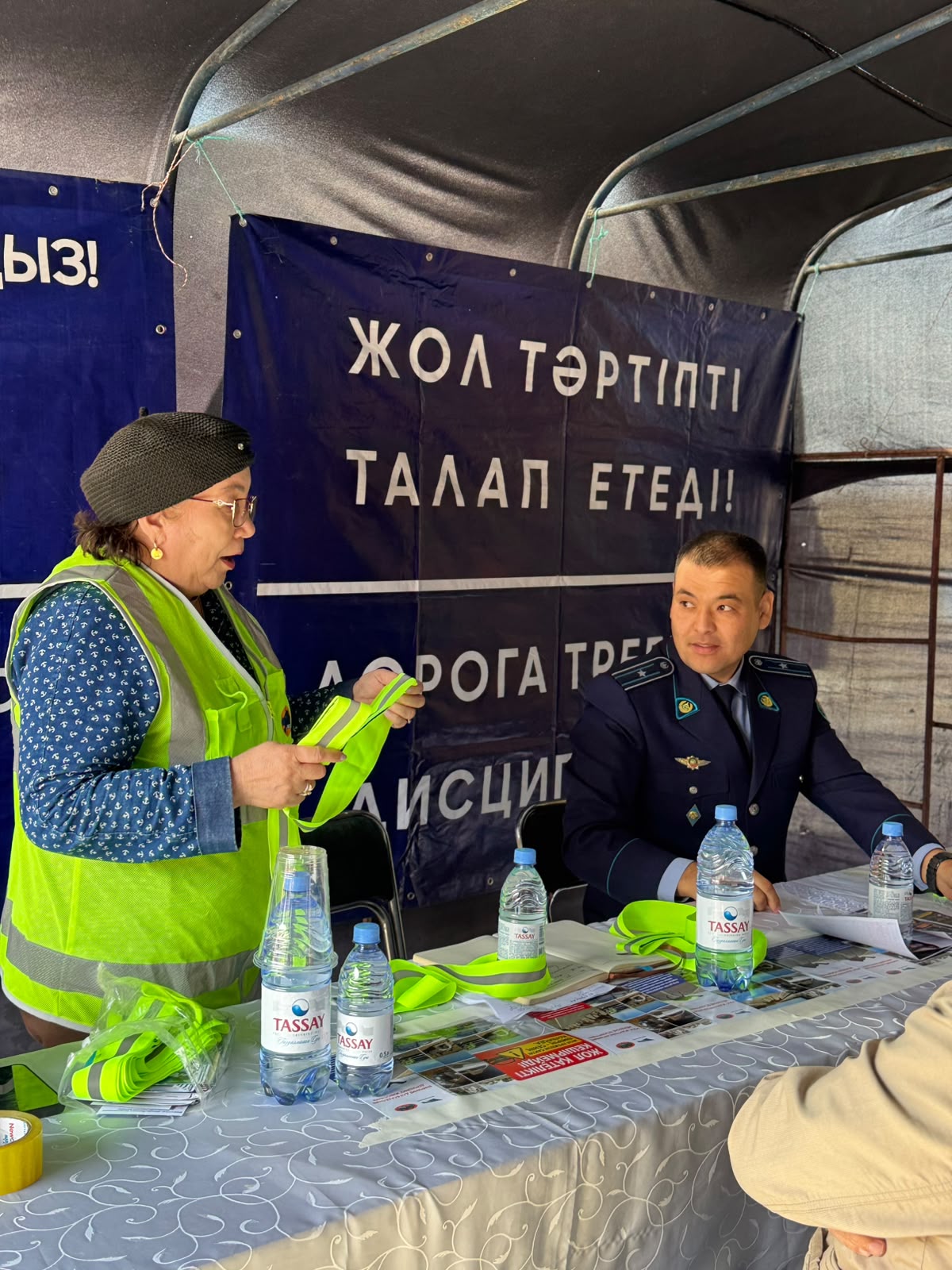 Жол тәртібін насихаттайтын шарада полиция қызметкері мен әйел адамның сөйлесуі.