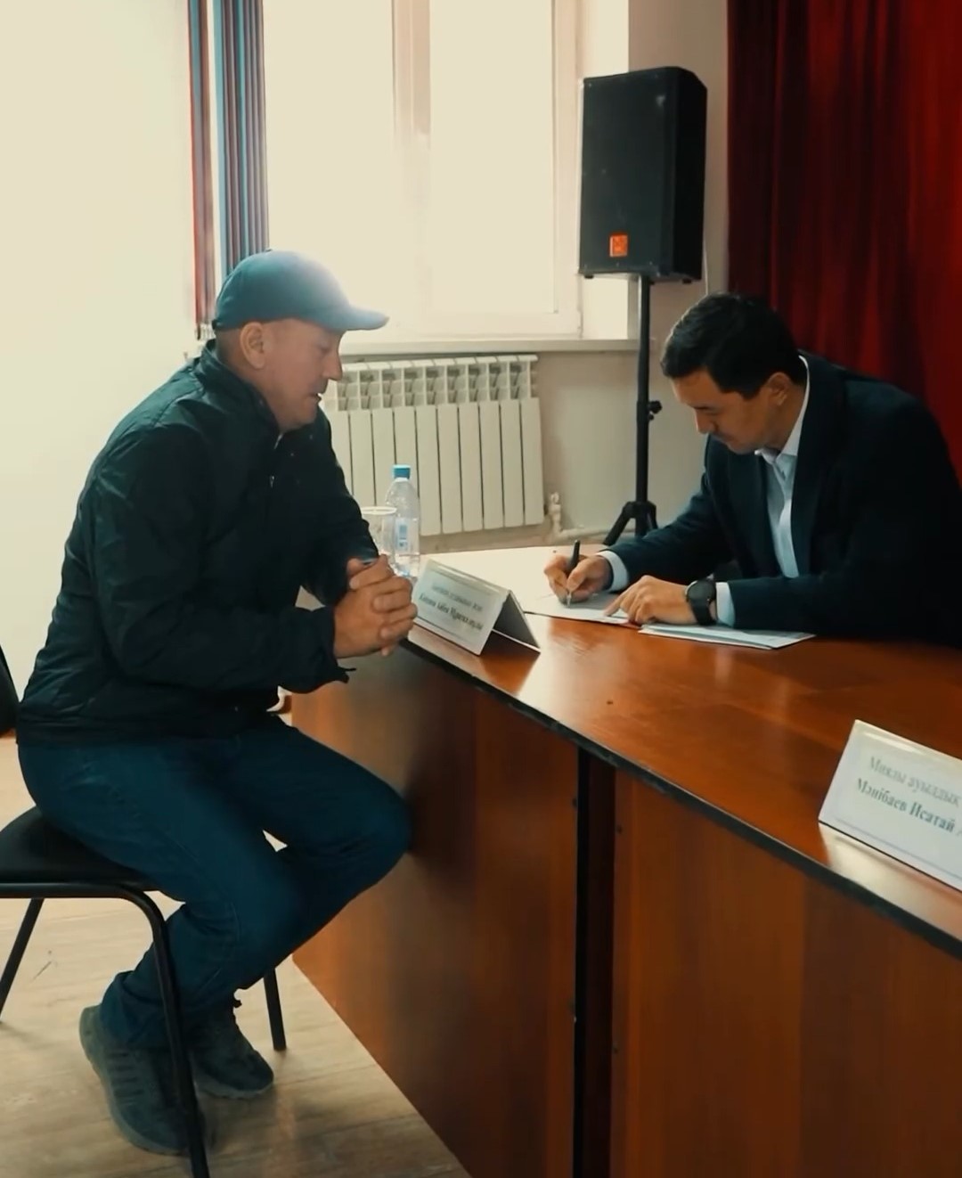 Келісімшартқа қол қойып жатқан екі ер адам.