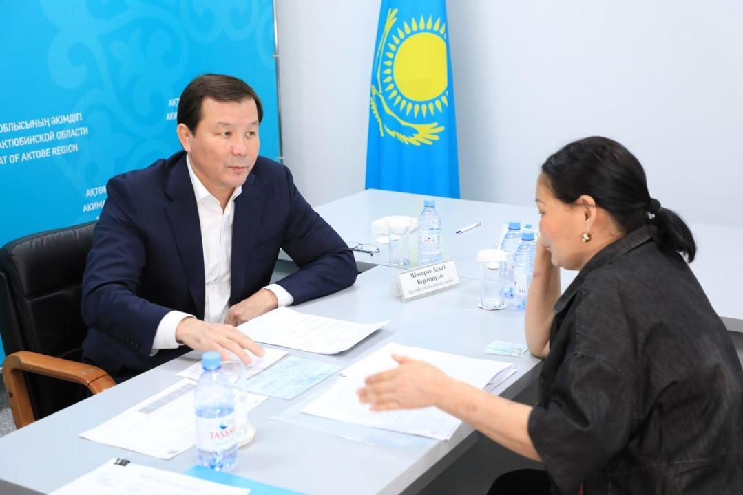 Көк костюм киген ер адам мен әйелдің келіссөз кезінде үстел басында құжаттармен жұмыс істеп отырғаны.