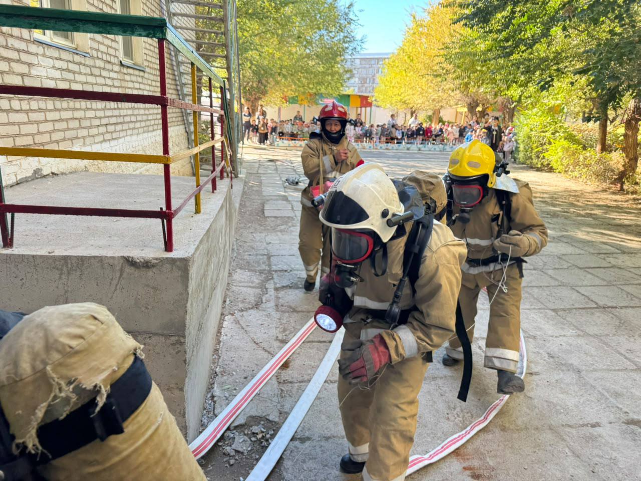 Арнайы киімі мен жабдығы бар өрт сөндірушілердің ғимарат жанындағы жаттығуы.