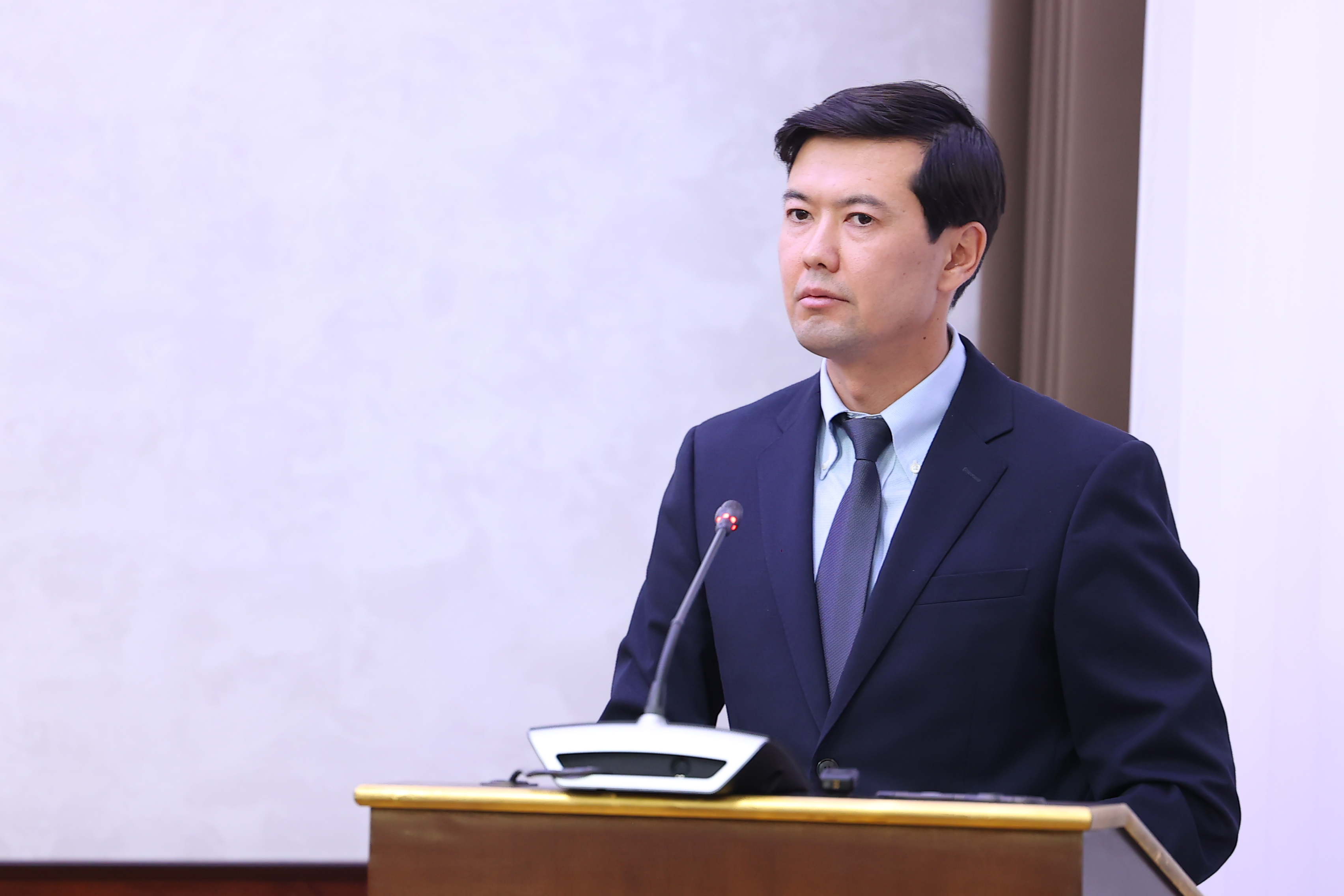 Кілемдік костюм киген ер адам трибунада тұр.