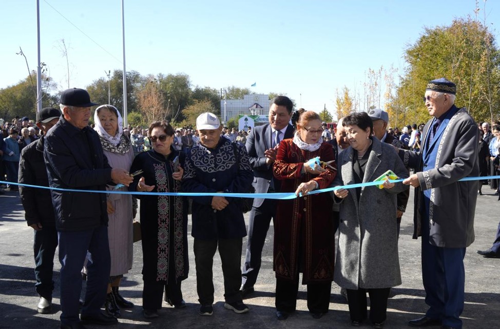 Көк лентаны кесіп, жаңа нысанды ресми түрде ашатын адамдар тобы.