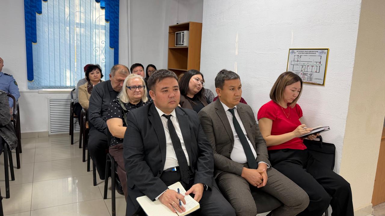 Жиналысқа жиналған костюм киген адамдар тобы.