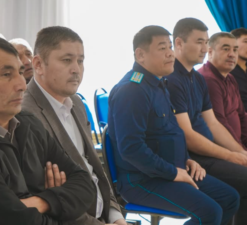 Жиналыста отырған ер адамдардың тобы.
