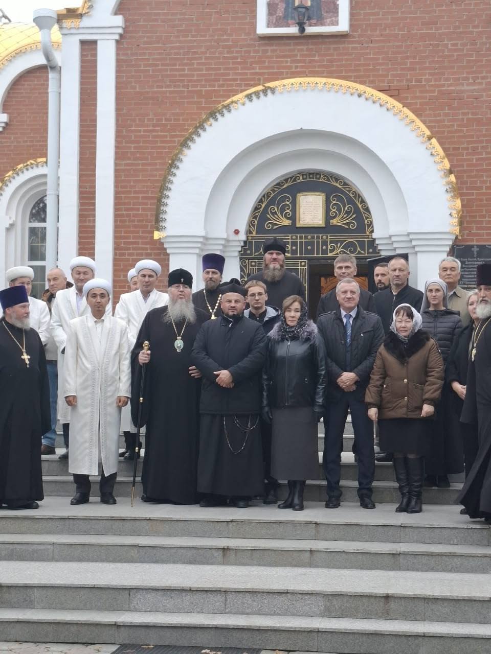 Шіркеудің алдында тұрған діни қызметкерлер мен келулердің топтық суреті.