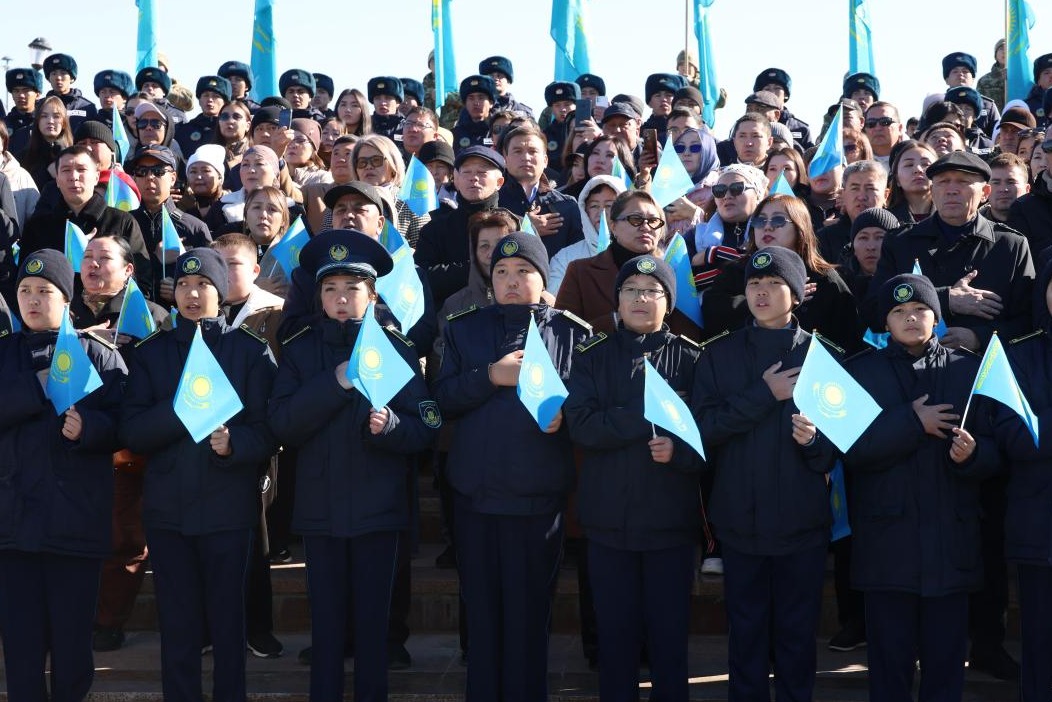 Қазақстан туларын ұстап тұрған форма киген балалар мен жиналған адамдар.