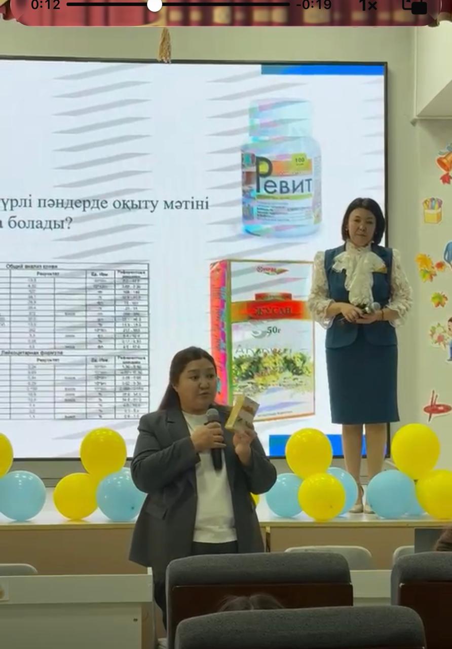 Экран алдында баяндама жасап тұрған екі әйел. Фонда презентация және түрлі-түсті шарлар.