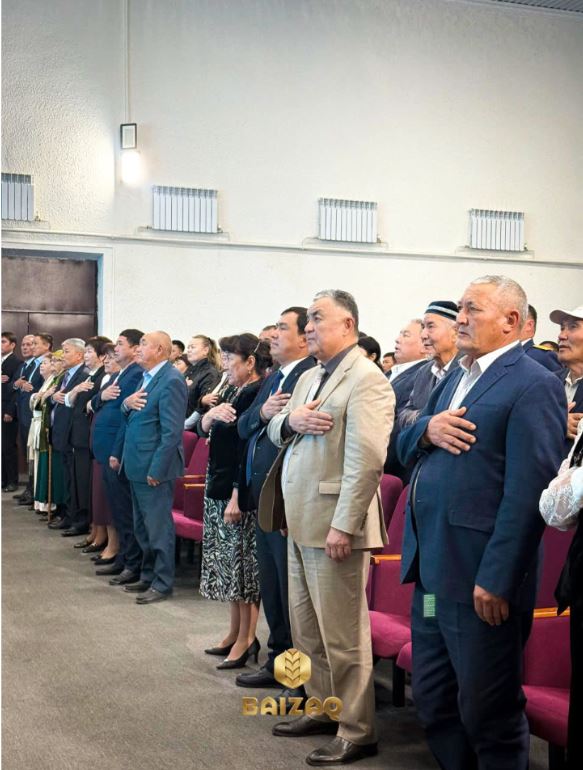 Қолын кеудесіне қойып, гимн айтып тұрған адамдар тобы.
