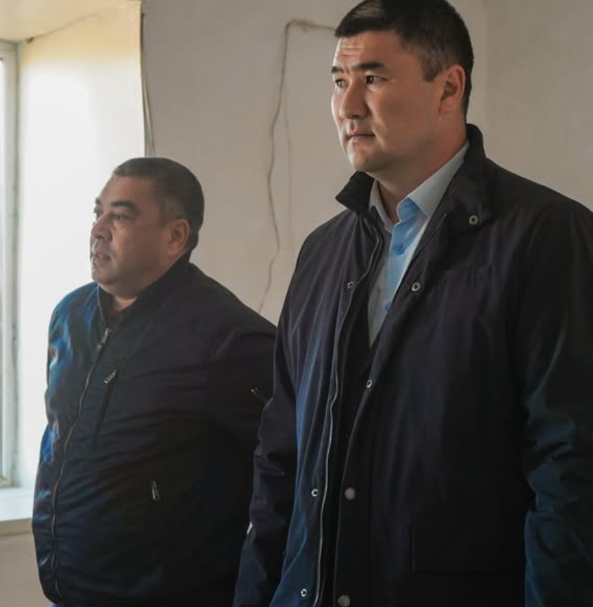 Көк куртка киген екі ер адам.