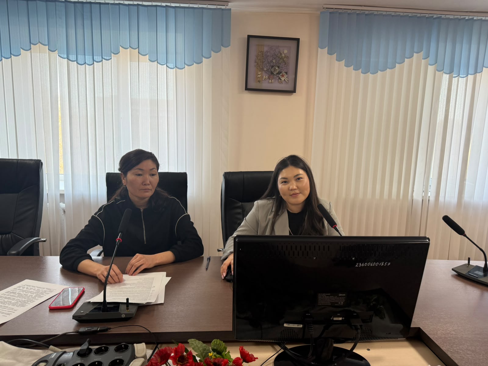 Кеңседе үстел басында отырған екі әйел.