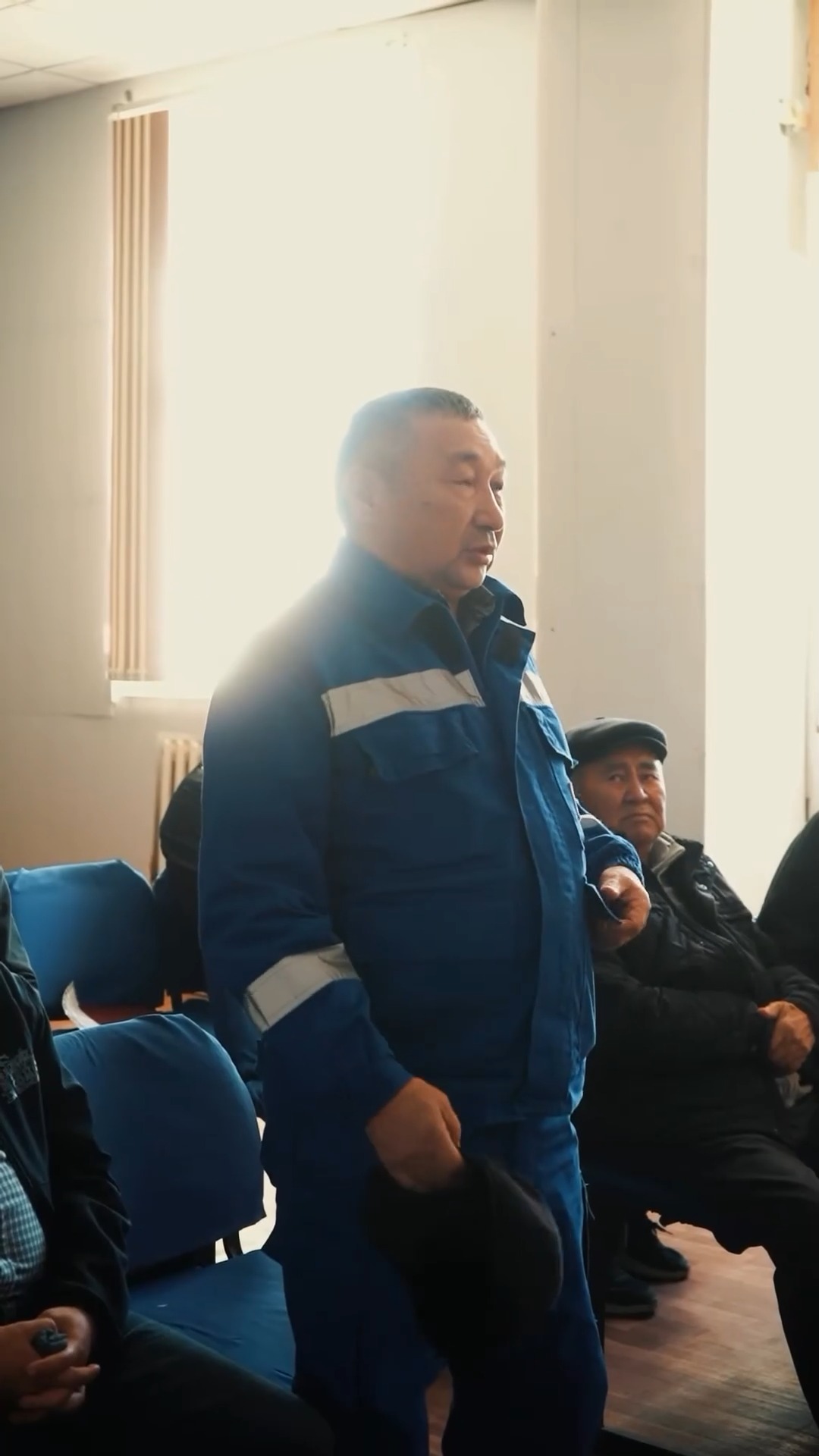 Көк түсті жұмыс киімін киген ер адам.