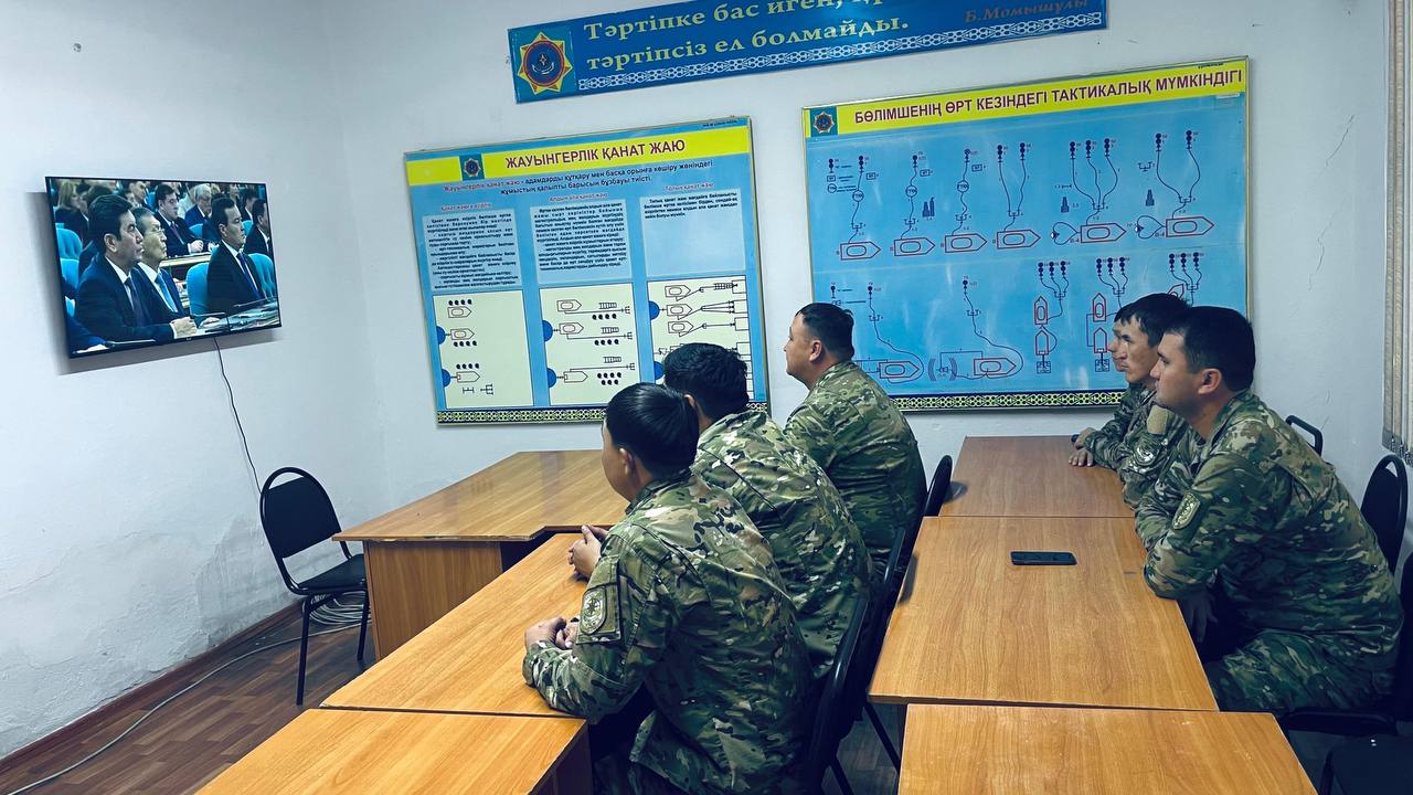 Әскери формадағы сарбаздар сыныпта монитор мен тактикалық схемаларды қарап, оқудан өтуде.