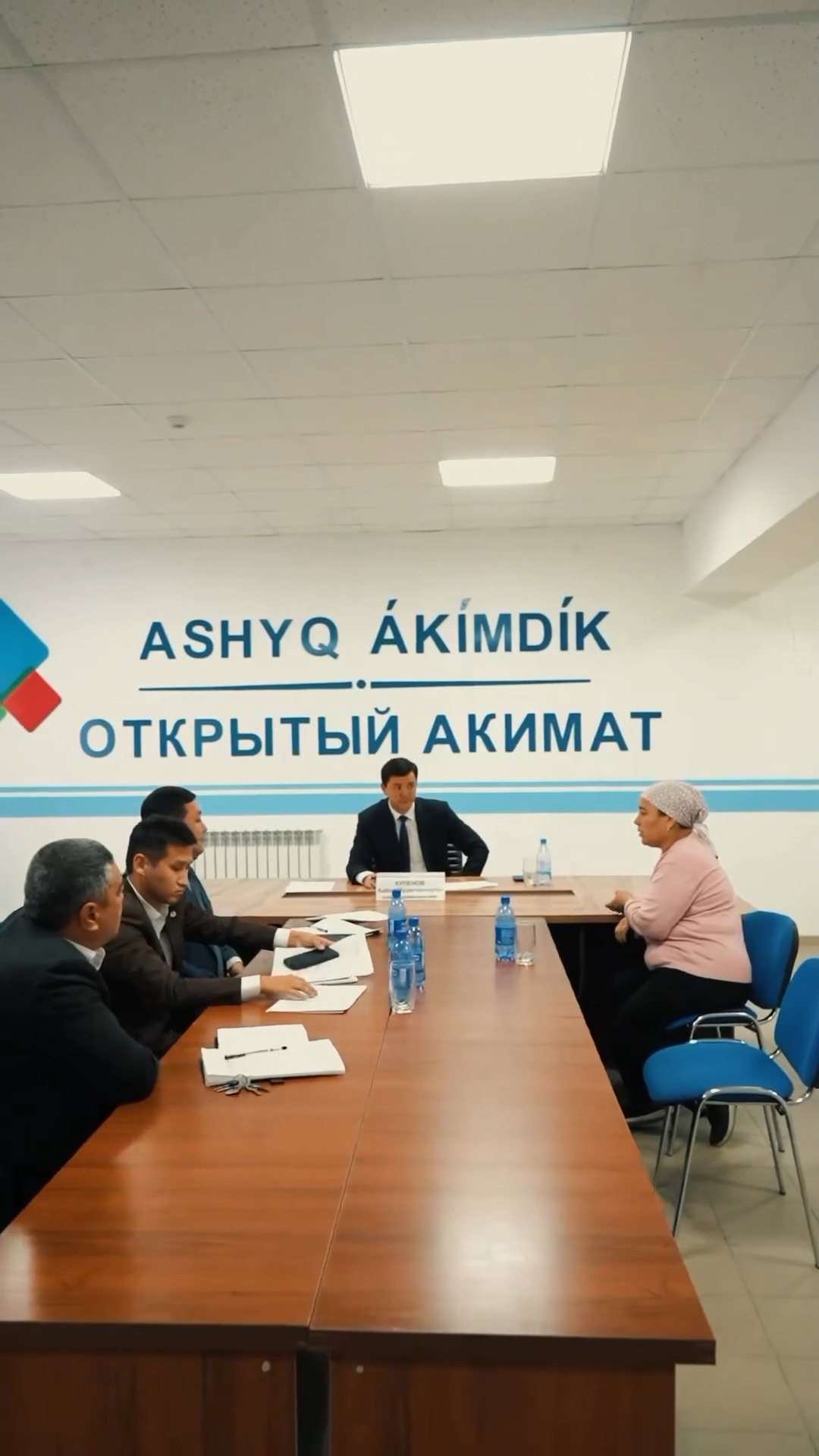«Ашық әкімдік» кеңсесіндегі кездесу: әкім мен азаматтардың үстел басындағы сөйлесуі.