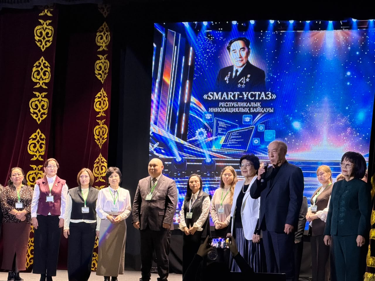 «SMART-ҰСТАЗ» республикалық инновациялық байқауының сахнасында тұрған мұғалімдер мен ұйымдастырушылар.