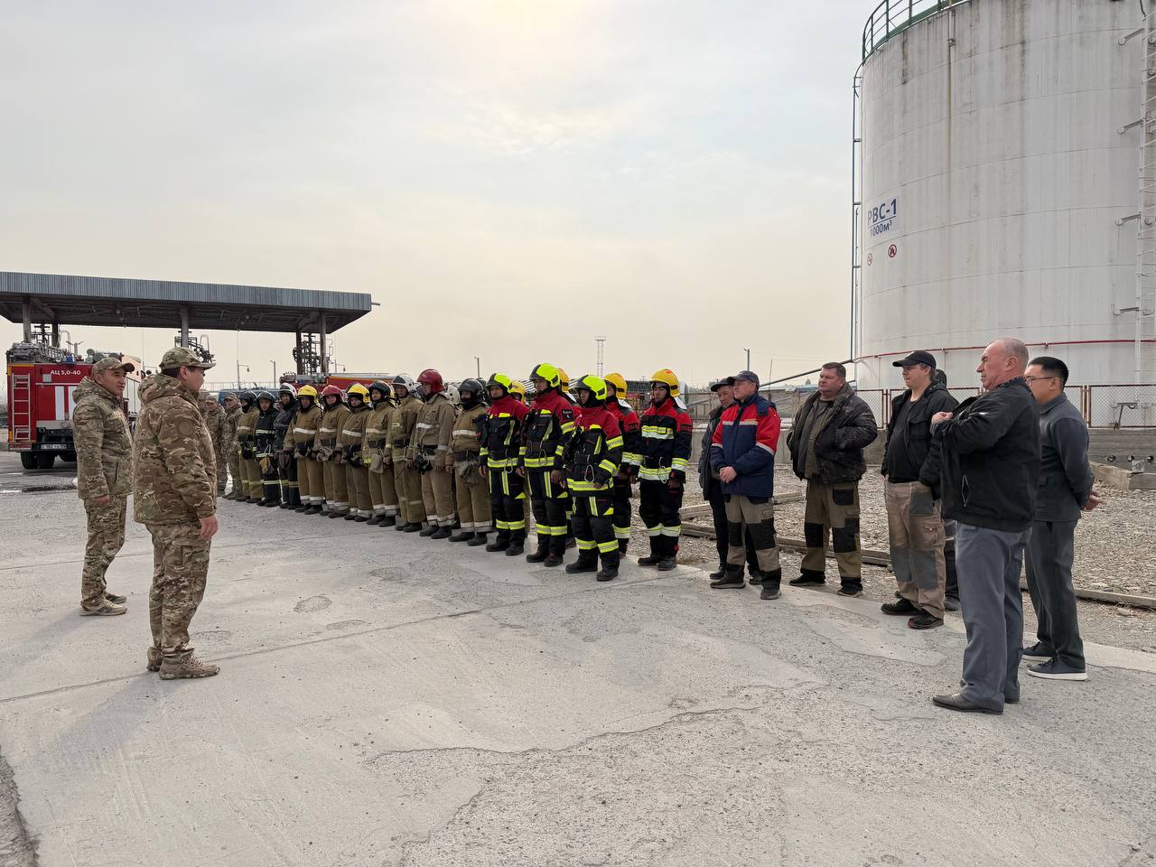 Өрт сөндірушілер мен әскерилердің сызылыста тұрған тобы.