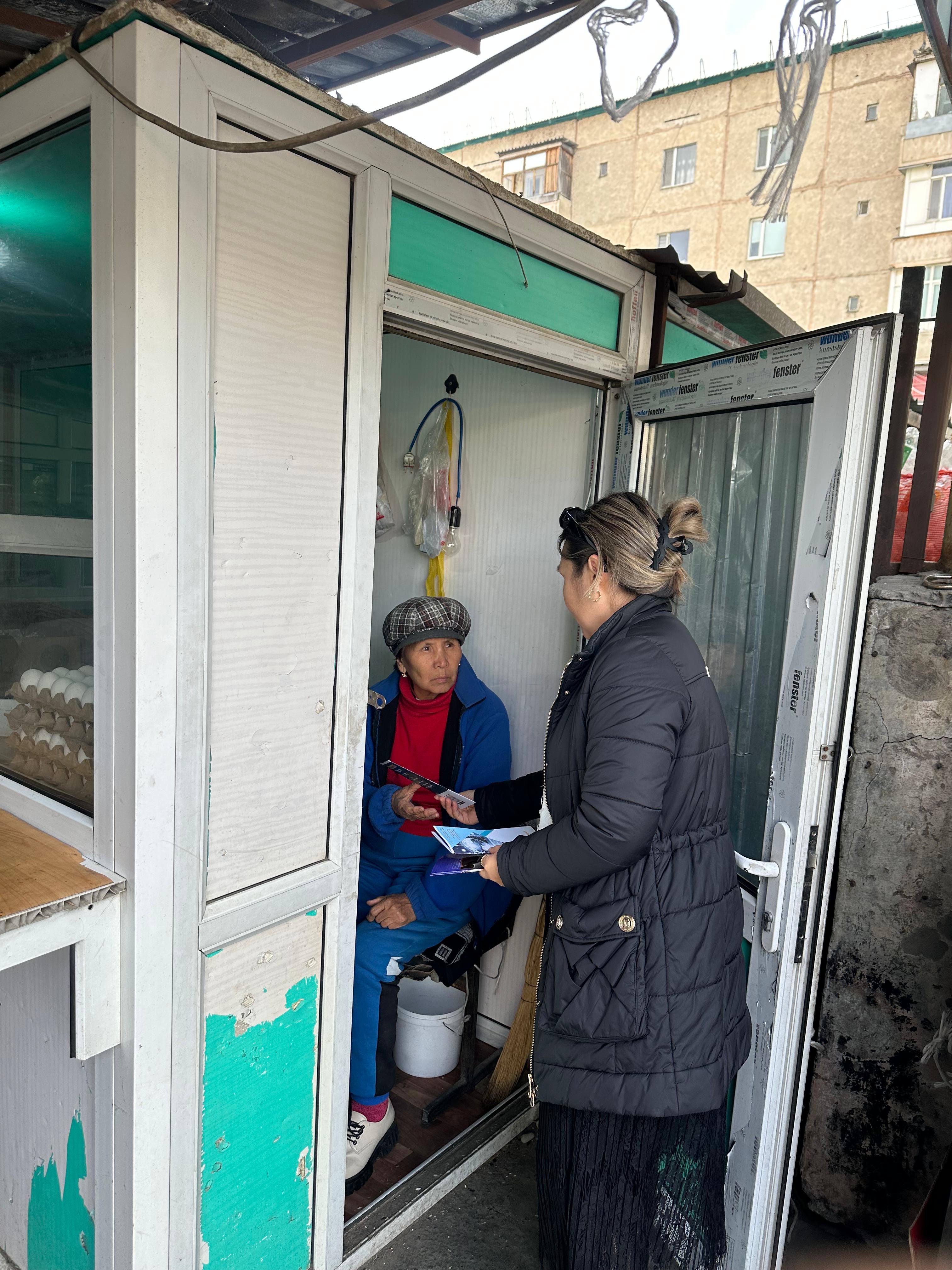 Кішігірім дүкеннің алдында тұрған әйел мен ішіндегі сатушының сөйлесуі.